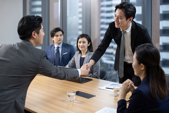 Successful Chinese business people shaking hands in meeting room