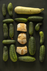 Flat lay with cucumbers and home baked bread on dark background - 622297879