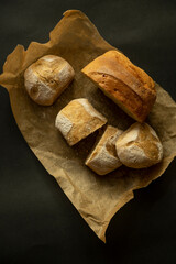 Flat lay with few pieces of home baked bread on coking brown paper and black background - 622298004