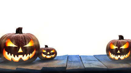 Three lit Jack-o-Lantern, halloween pumpkin lanterns on a wooden product display table with an isolated transparent background. - obrazy, fototapety, plakaty