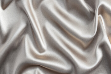 Abstract silver satin background of luxurious fabric. soft gentle waves of fabric. The golden texture of the fabric. Festive, New Year's background
