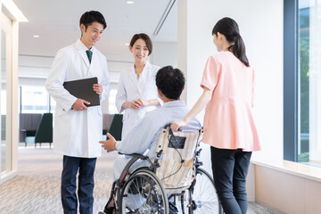 病院で車椅子に乗った入院患者と話す医者