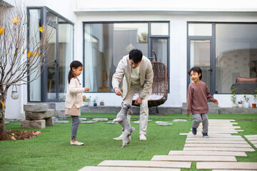 Happy young Chinese family playing with pet dog in the courtyard