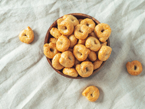 Traditional italian snack taralli or tarallini in wooden bowl over light linen napkin background. Rustic shot of taralli appetizer with copy space. Top view or flat lay.