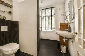 a bathroom with black tile and white tiles on the walls, along with a toilet in the center of the room