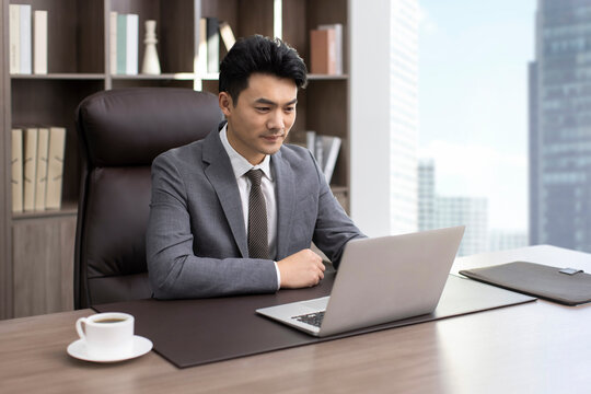 Successful Chinese businessman using laptop in office