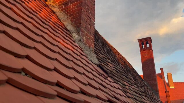 4K close up video with the ceramic red tiled roof of an old house. Tile roof video. Pan camera movement.