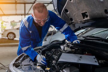 Close-up view of auto mechanic working on car engine in garage. Repair service