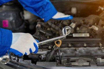 Close-up view of auto mechanic working on car engine in garage. Repair service