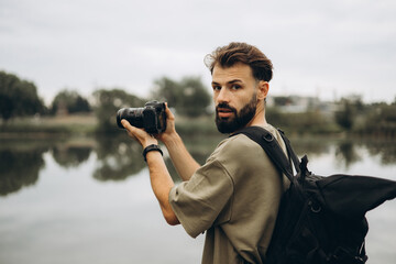 a young man with a modern SLR camera in his hands on a natural background
