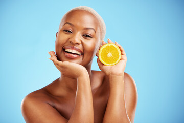 Portrait, beauty and orange with a black woman in studio on a blue background for fruit nutrition. Smile, skincare or diet with a happy young female person holding food for natural health or wellness