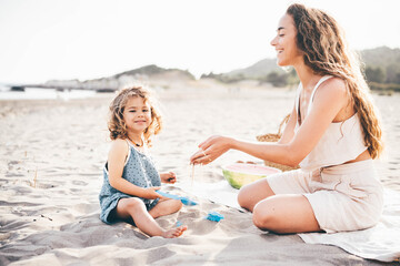 Mother playing with little daughter on the beach.