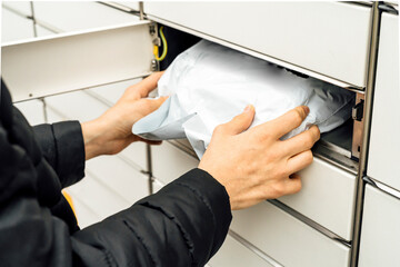 A man with a box in his hands near the self-service mail terminal. Parcel delivery machine. Person...