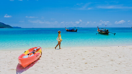 Koh Lipe Island Southern Thailand with turqouse colored ocean and white sandy beach at Ko Lipe. a Asian Thai woman on vacation in Thailand relaxing at the beach looking at the ocean