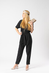 A young blonde woman in a smart black trouser suit with a clutch bag in her hand