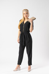 A young blonde woman in a smart black trouser suit with a clutch bag in her hand