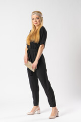A young blonde woman in a smart black trouser suit with a clutch bag in her hand
