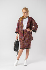 A young blonde in a casual warm office outfit, with a bag in her hands.