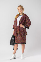 A young blonde in a casual warm office outfit, with a bag in her hands.