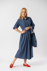 Young blonde woman in an elegant casual fashionable dress with a bag in her hands
