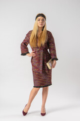 A young blonde in an elegant elegant outfit with a clutch bag in her hands.