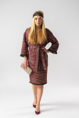 A young blonde in an elegant elegant outfit with a clutch bag in her hands.