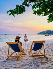 couple relaxing at a beach chair on the beach of Koh Lipe Thailand during sunset, men and women on vacation in Thailand