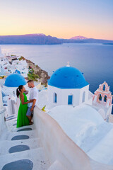 Couple hugging and kissing on a romantic vacation in Santorini Greece, men and women visit the whitewashed Greek village of Oia .