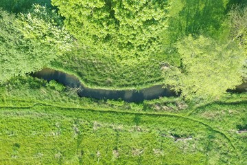 Naklejka na ściany i meble defaultDrone perspective over green fields of Hook, Hampshire, England, river path between trees and grass, drone perspective