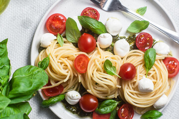 Obraz na płótnie Canvas Spaghetti with mozzarella, tomatoes, basil and pesto sauce. Pasta Caprese
