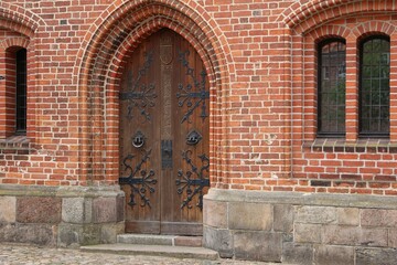 closeup of a very old large wooden door of a church with metallic decorations on the wood