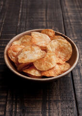 Bowl with potato crisps chips on wooden board. Junk food