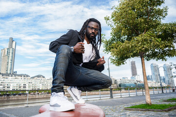 elegant and fashionable young black man of African ethnicity posing crouched looking at the camera