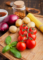 Fresh organic tomatoes with vegetables on wooden board. Potatoes,onion,sause.spices,basil