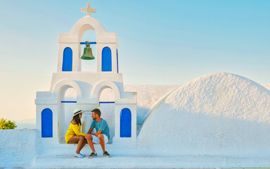 Young couple of men and women tourists visit Oia Santorini Greece on a sunny day during summer with...
