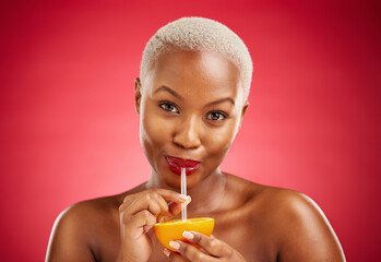 Black woman, portrait and drinking orange for vitamin C, diet or natural nutrition against a red...