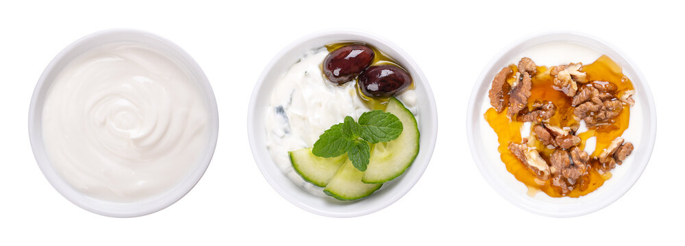 Cream yogurt, tzatziki, and Greek yogurt with honey and roasted walnuts, in white bowls. Stirred yoghurt (left), Greek dip sauce, mixed with cucumber and garlic (center), and Yiaourti me meli (right).