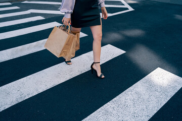 Woman walking along the crossroads with shopping bags. 
People shopping in the city