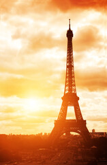 Famous landmark of Paris - Eiffel tower, Champ-de-mars, Paris, France. On sunset sky background. Photo toned in orange color