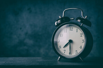 classic alarm clock on a table. Dark background