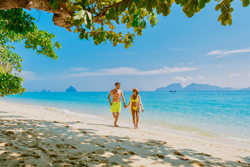 the backside of a couple of men and women sitting at the beach of Koh Kradan island in Thailand during vacation on a sunny day at holiday on the beach