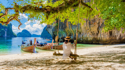 women on a swing at the Tropical lagoon of Koh Loa Lading Krabi Thailand part of the Koh Hong Islands in Thailand. beautiful beach with limestone cliffs and longtail boats