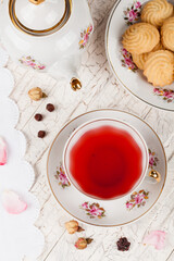 cup of red tea and biscuits on white serving table