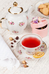 cup of red tea and biscuits on white serving table