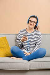 Obraz premium Beautiful woman at home sitting on the sofa and listen music
