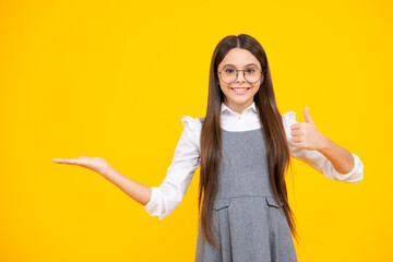 Look at advert. Teenager child points aside shows blank copy space for text promo idea presentation, poses against yellow background.