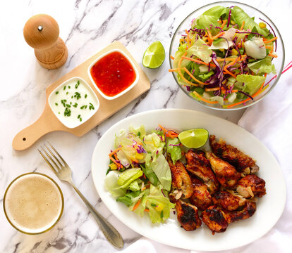 Roasted chicken wings with salad, top view