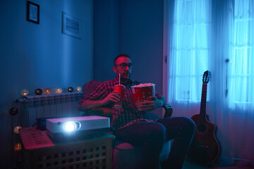 Man enjoying popcorn and juice while watching movie at home projector.