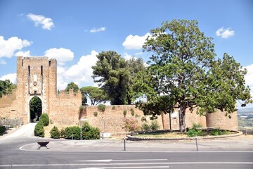 a big tree next to the old city entrance and the city walls of Orvieto in Italy