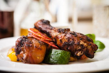 Red Orange glazed chicken with grilled vegetables served on a white plate